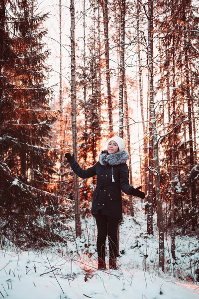 Söt flicka i en vit hatt och en jacka på en bakgrund av en vinter skog. — Stockfoto