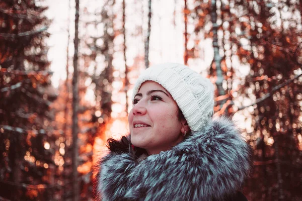 एक सफेद टोपी में सुंदर लड़की और एक शीतकालीन जंगल की पृष्ठभूमि पर एक जैकेट . — स्टॉक फ़ोटो, इमेज