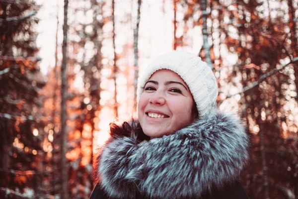 Pen jente med hvit lue og jakke bak vinterskogen. . – stockfoto