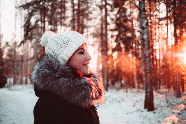 Mädchen mit weißem Hut und Jacke vor dem Hintergrund eines Winterwaldes. — Stockfoto