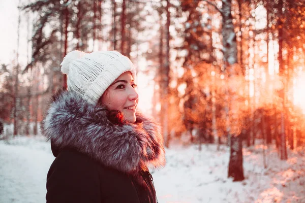 Young woman in a white hat and a jacket on a background of a winter forest. — Stock Photo, Image