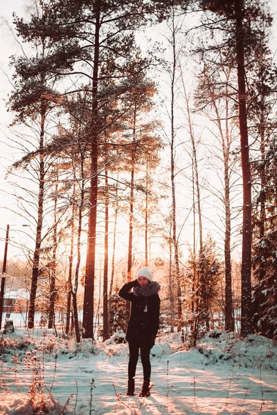 Söt flicka i en vit hatt och en jacka på en bakgrund av en vinter skog. — Stockfoto