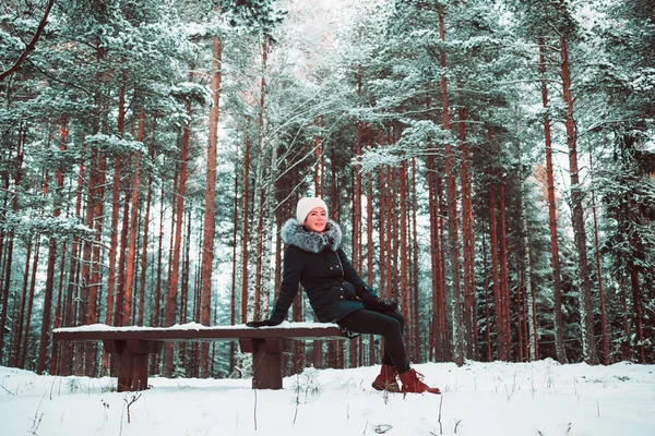 Slender girl sits on a bench in the winter. — Stock Photo, Image