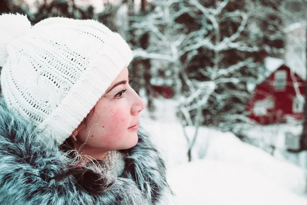 Young woman in a white cap and a jacket on a background of a winter forest. — Stock Photo, Image