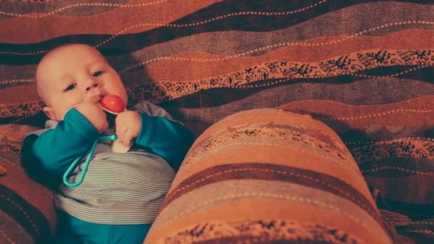 Camera moves from the right on left and removes the small baby as he plays with a toy. — Stock Video