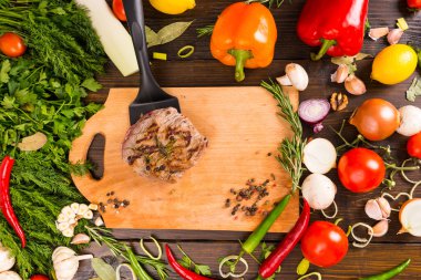 Patty üzerinde spatula ve sebzeler kesme tahtası üzerinde