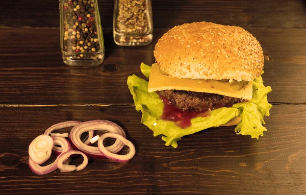 Cheeseburger s plátky červené cibule na stole — Stock fotografie