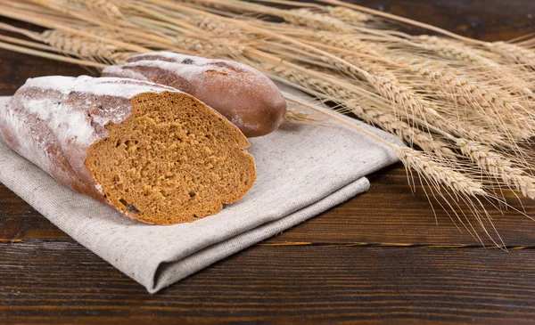 Pan de centeno cortado por la mitad junto al trigo —  Fotos de Stock