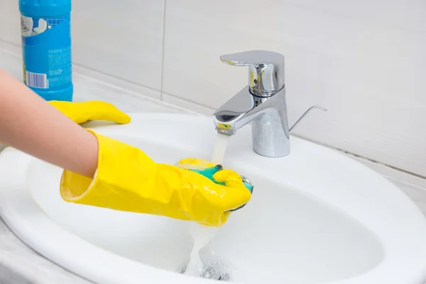 Housewife rinsing off a sponge for cleaning — Stock Photo, Image