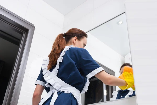 Low angle view on maid cleaning mirror — Stock Photo, Image
