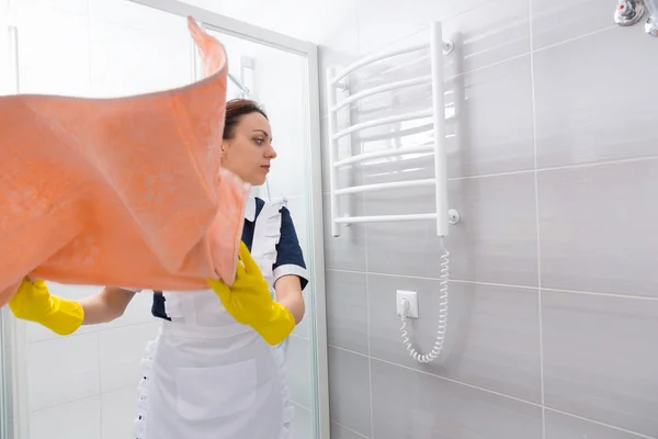 Hushjelp som tar av håndkle fra stativet på badet – stockfoto