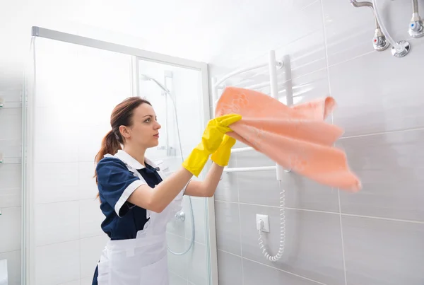 Домработница выпрямляет полотенце в ванной комнате — стоковое фото