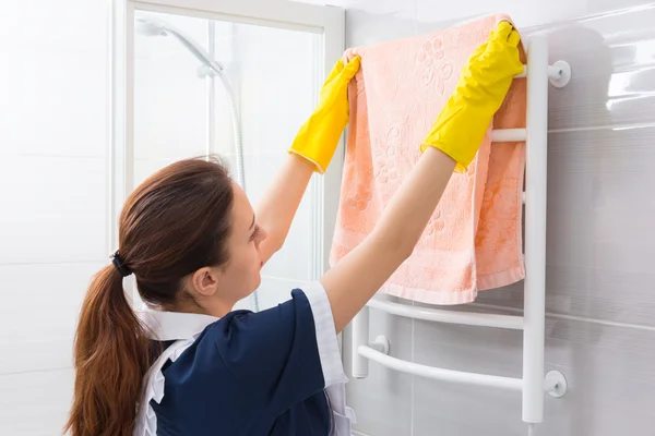 Mucama reemplazando toalla en rack en el baño — Foto de Stock