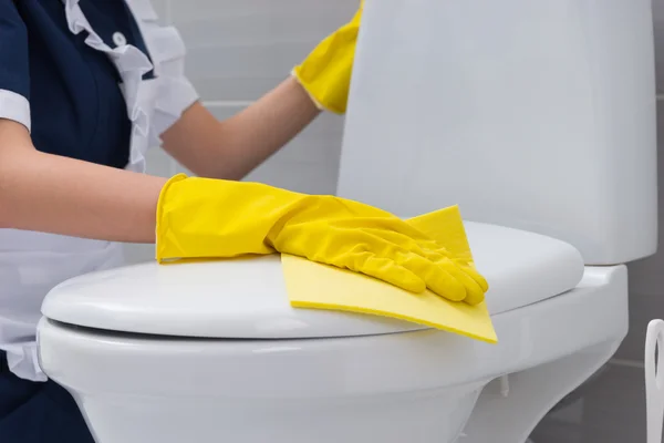 Housekeeper cleaning a white toilet lid — Stock Photo, Image