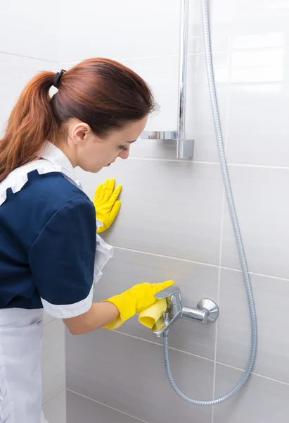 Housekeeper cleaning the fittings in a shower — Stockfoto