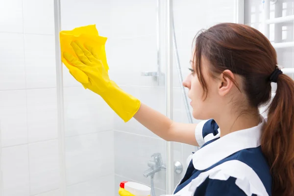 Housekeeper cleaning the glass shower cubicle — Stock Photo, Image