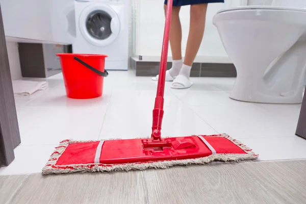 Ama de casa fregando el piso en un baño — Foto de Stock