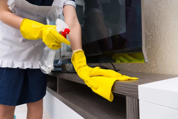 Maid cleaning a television cabinet — Stock Photo, Image