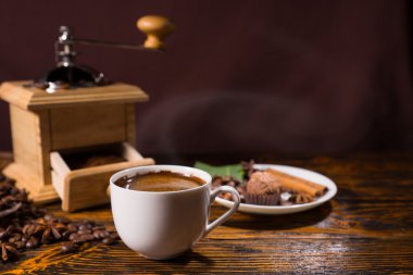 Wooden coffee grinder by white mug and treat