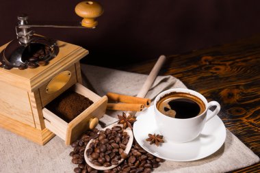 Grinder with freshly ground coffee beside beans