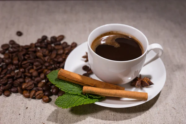 Taza llena de café con palitos de canela y menta — Foto de Stock