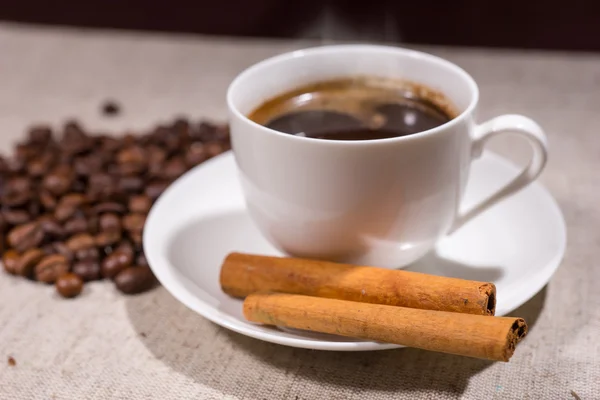 Cinnamon sticks in focus beside hot coffee — Stockfoto