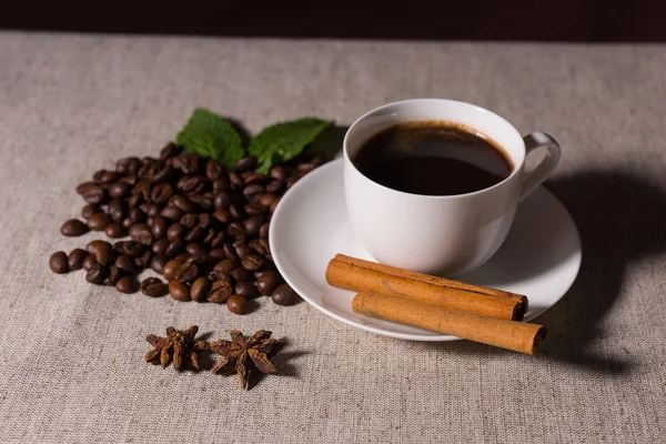 Coffee with cinnamon, mint and beans on tablecloth — Stock Fotó