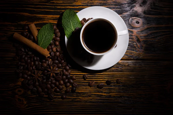 Homályosan megvilágított csésze kávé levelekkel és babbal — Stock Fotó