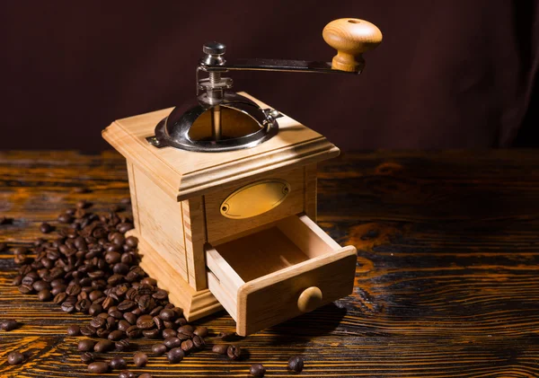 Wooden coffee grinder with scattered beans