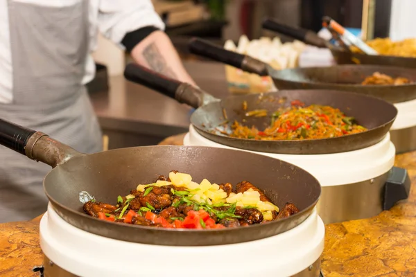 Reihe von Woks mit frisch gekochtem Essen auf dem Tisch — Stockfoto