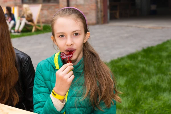 Young girl sucking a chicken shaped lollipop — Stock Photo, Image