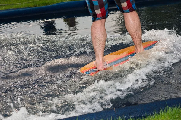 Man riding a small surfboard along a water slide — Stock Photo, Image