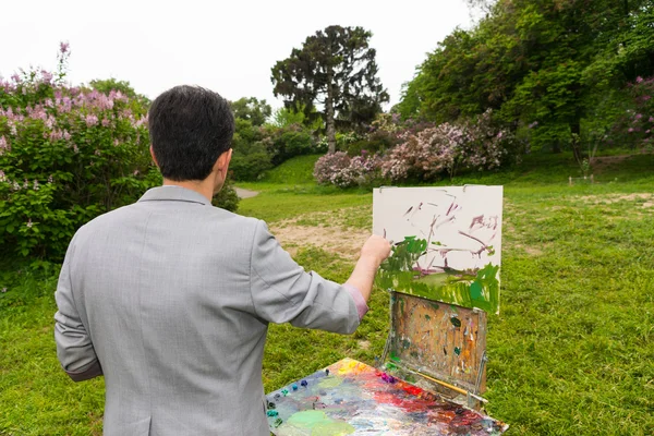 Middle-aged man painter standing in front of  a sketchbook  in a — Stock Photo, Image