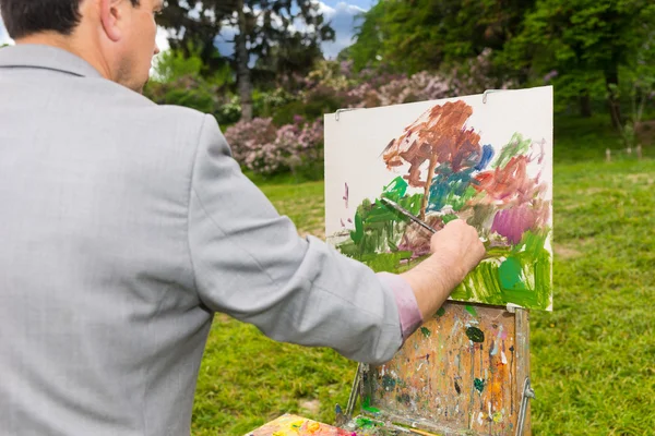 Male artist painting a beautiful sketch of picture outdoors — Stock Photo, Image