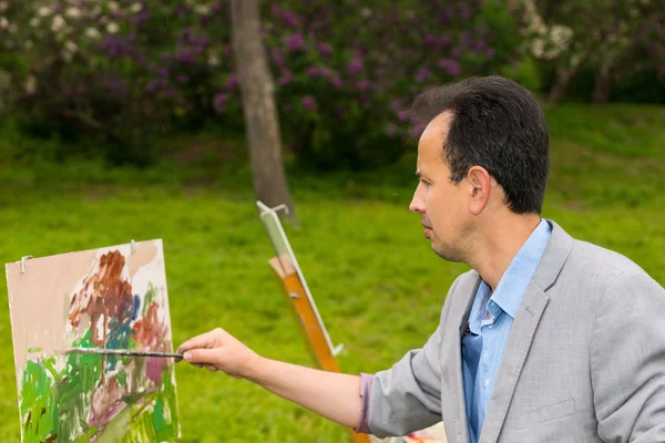 Artista masculino durante a criação uma obra-prima em um parque — Fotografia de Stock