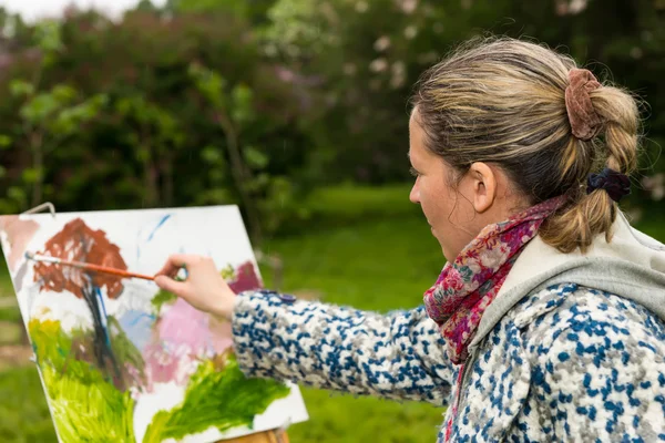 Kvinnliga kontemplativa artist paintig sista handen i en park — Stockfoto