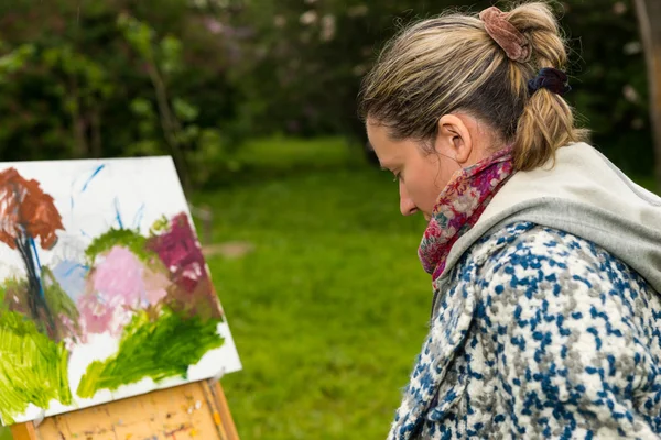 Kvinnliga kontemplativa målare tittar på hennes skiss i en park — Stockfoto