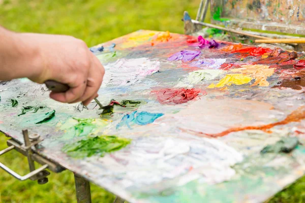 Mano di un artista mescolando i colori su un pa multicolore professinale — Foto Stock