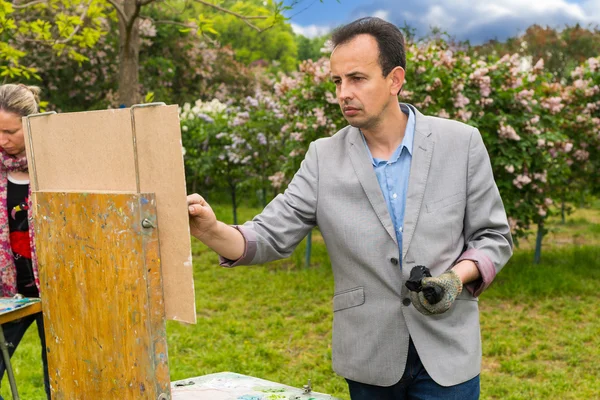 Mannelijke en vrouwelijke kunstenaars schilderen een meesterwerk in een park — Stockfoto