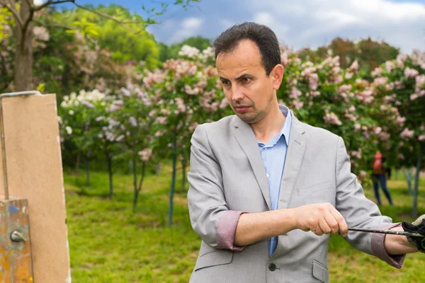 Middle-aged fashionable handsome male painter cleaning off his p — Stock Photo, Image