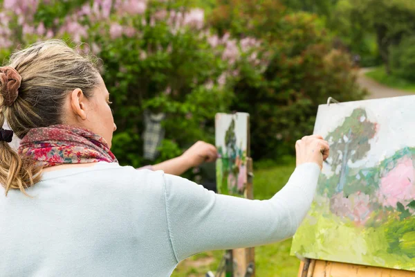 Bakifrån av en kvinna målare arbetar utomhus i parken eller gar — Stockfoto