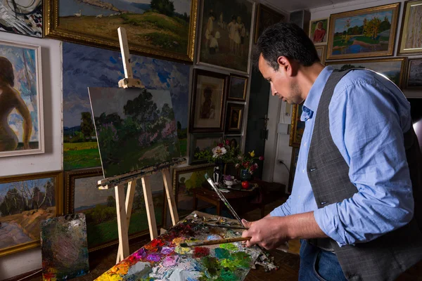 Artista masculino de meia-idade misturando cores em uma galeria — Fotografia de Stock