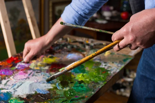 Pintor segurando pincéis profissionais em uma galeria — Fotografia de Stock