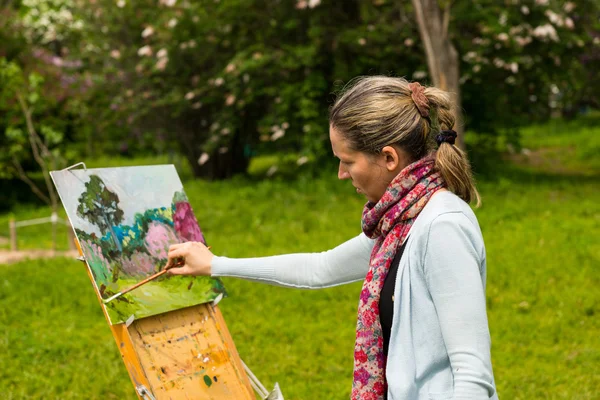 Vrouwelijke schilder schilderij buitenshuis — Stockfoto