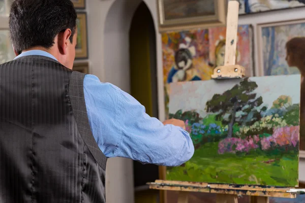 Erkek ressam bir galeride bir şövale üzerinde çalışıyor — Stok fotoğraf
