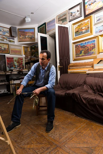 Pintor masculino pensativo sentado em seu estúdio — Fotografia de Stock