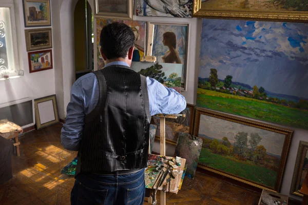 Pintor masculino trabalhando em um cavalete em um estúdio — Fotografia de Stock