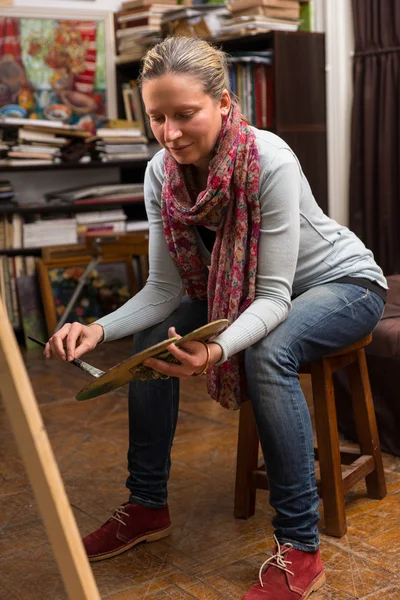 Mulher atraente sentado pintura em um estúdio — Fotografia de Stock