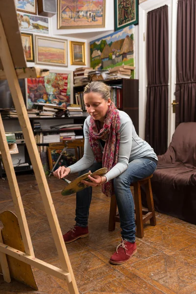 Aantrekkelijke vrouwelijke artiest vergadering schilderij in een studio — Stockfoto