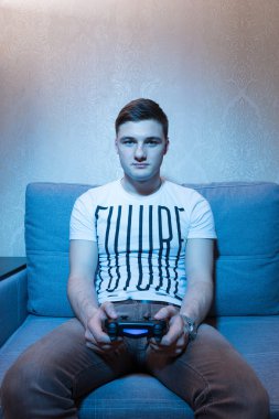 Genç adam evde kanepede otururken bilgisayar oyunu oynamak